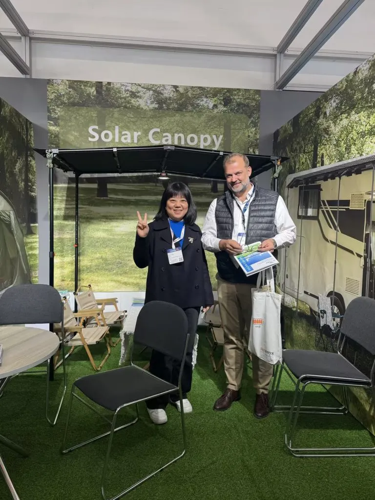 WistekEnergy representative Linda with international customers at renewable energy exhibition showcasing solar canopy and lithium energy solutions